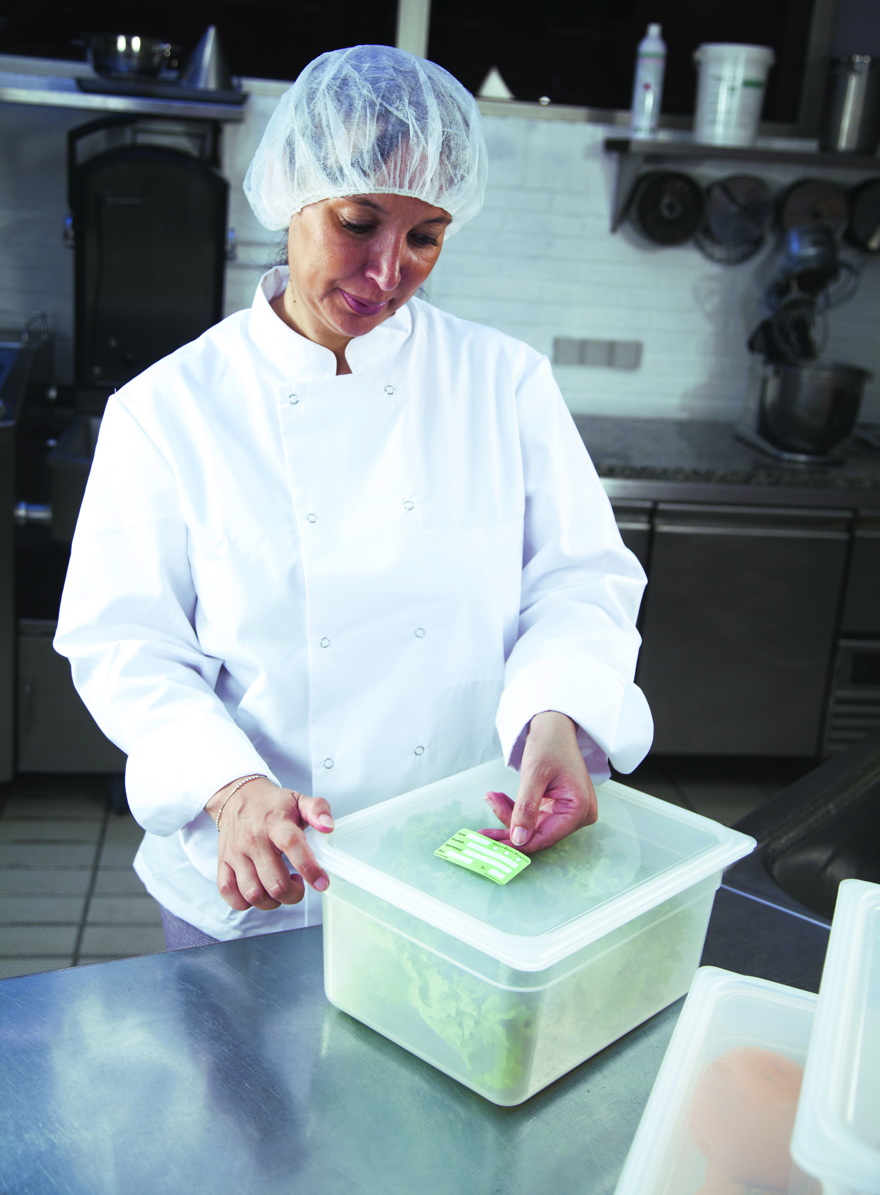 Cuisinier qui met des étiquettes prodate sur ses bacs gastro pour le plat témoin